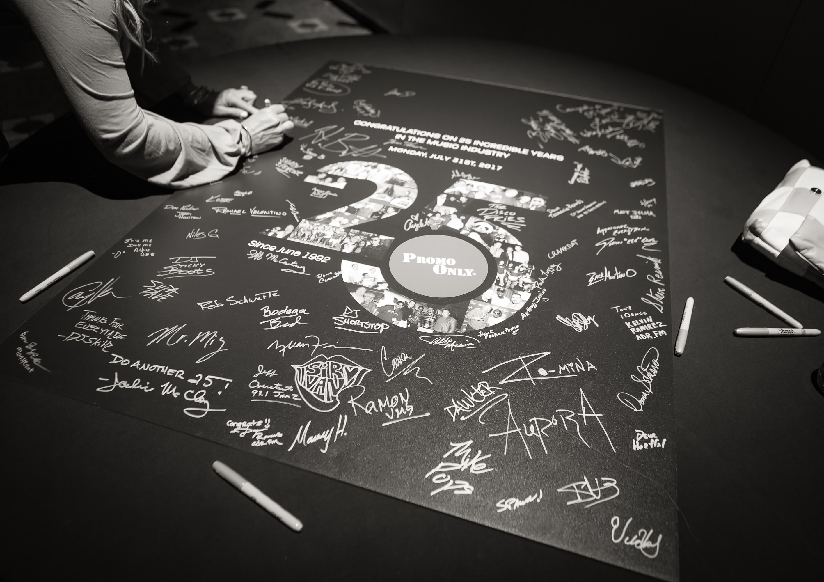 Promo Only's 25th Anniversary poster A person signs a poster